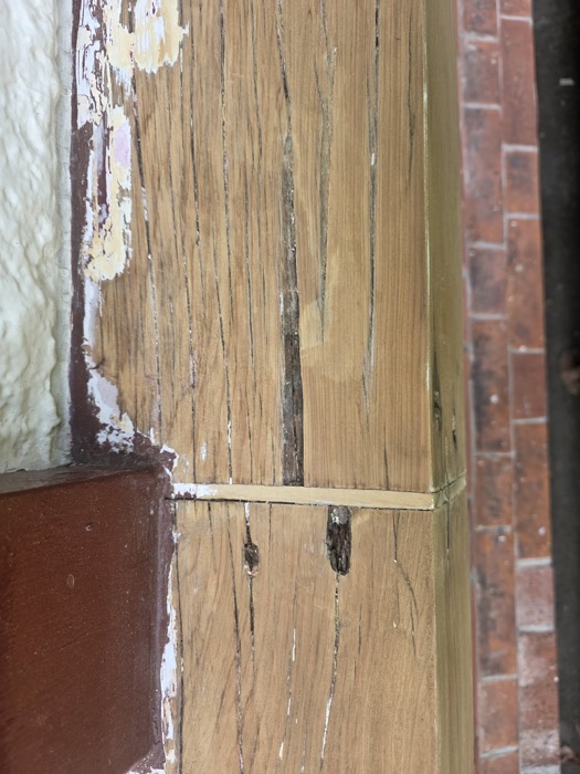 Rotted timber beside a brick wall